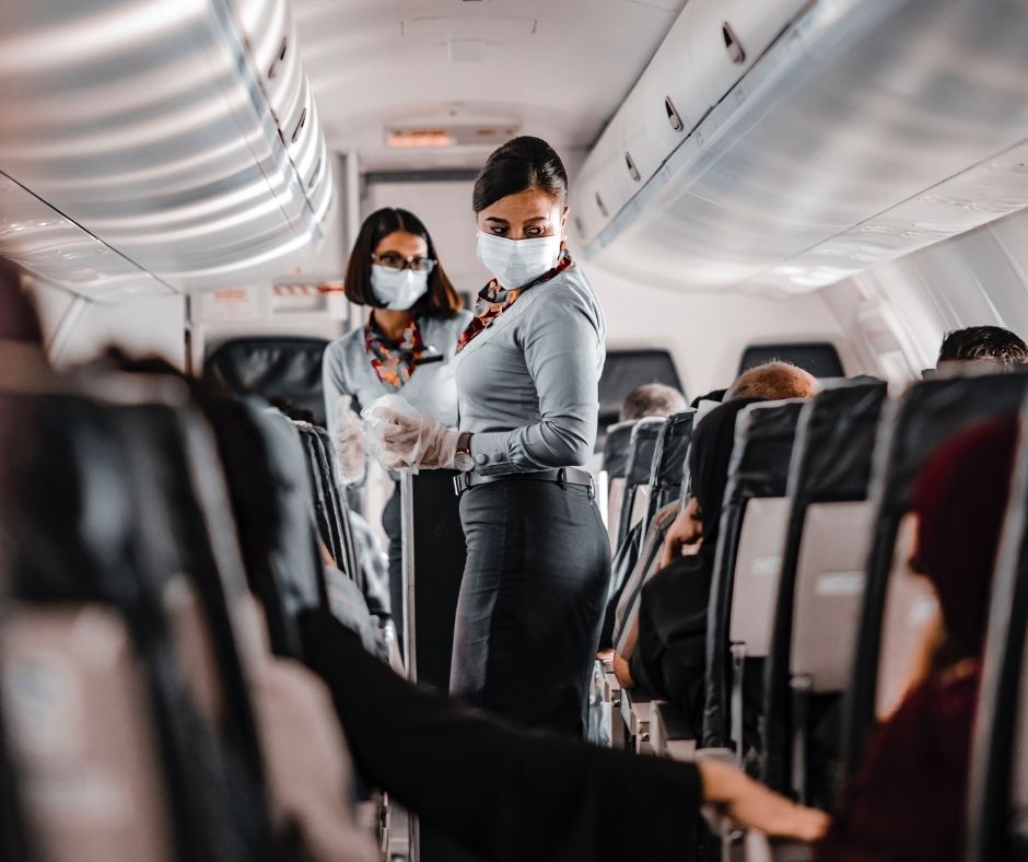 Air hostesses, wearing masks, assist passengers