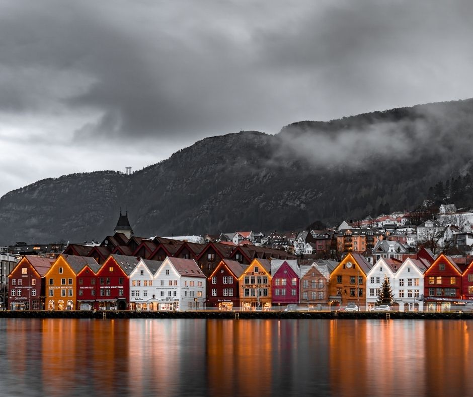 An overcast day in Norway as buildings are reflected in the still waters