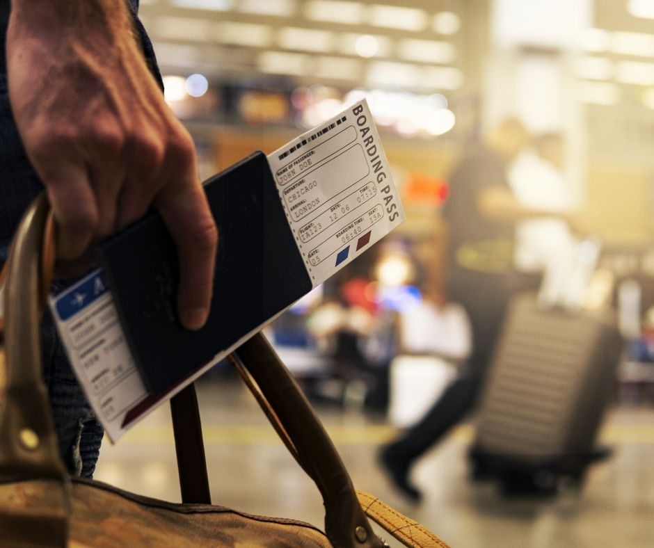 A man carrying his boarding pass and passport in an airport