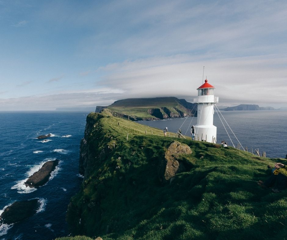 Beautiful white lighthouse is perched on a cliff over the Atlantic on the Faroe Islands
